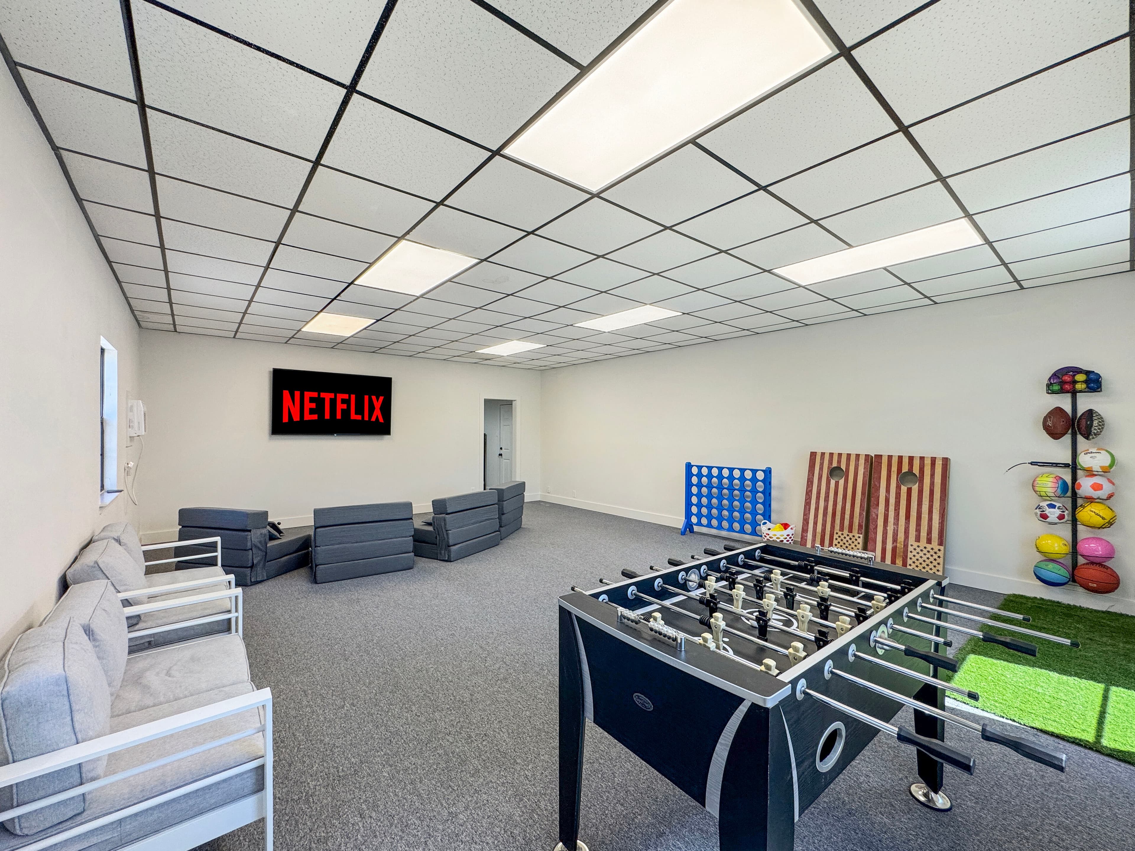 Game room with foosball, cornhole, putting turf, and TV